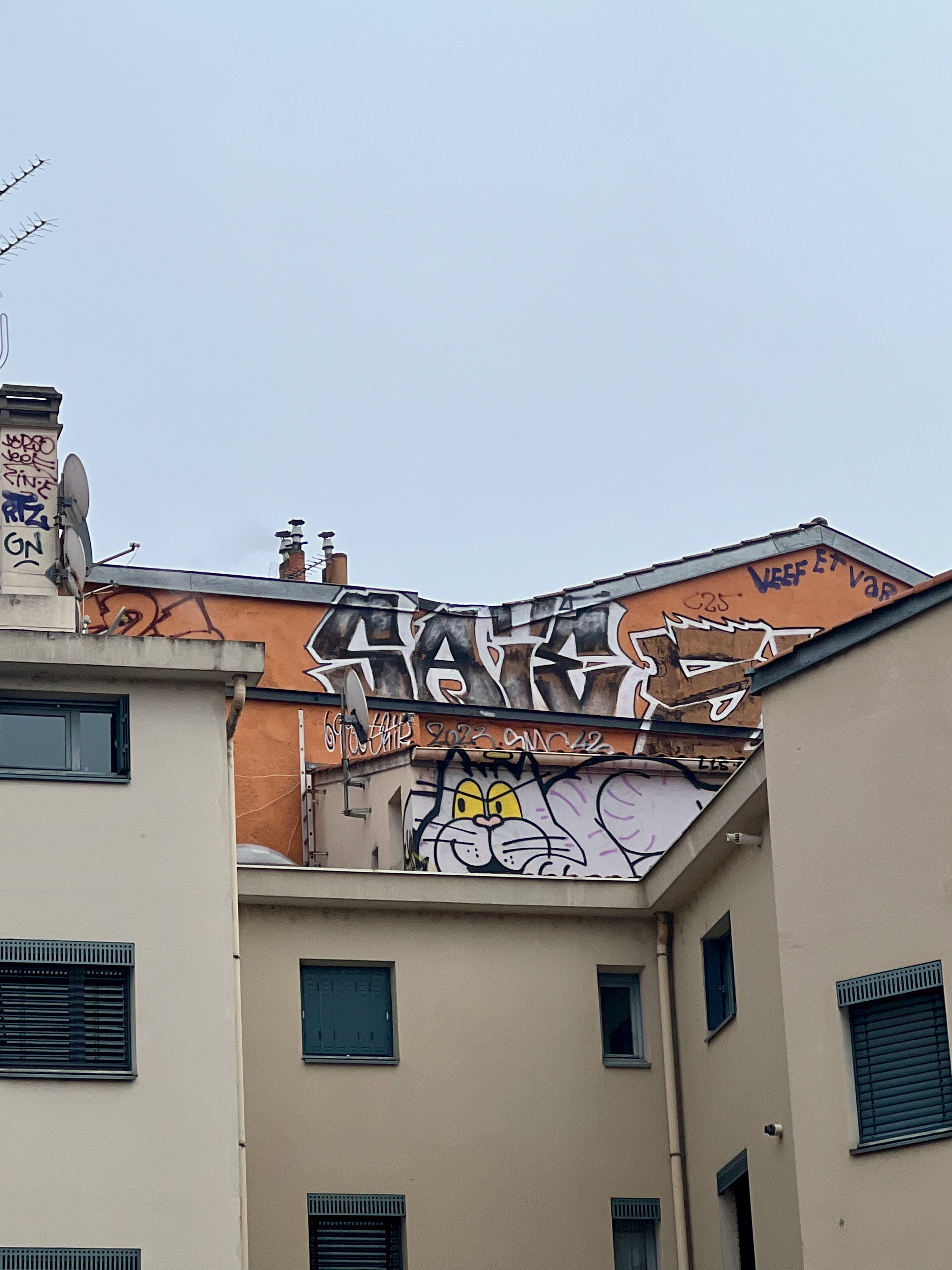 Rooftop graffiti and street art on an orange wall